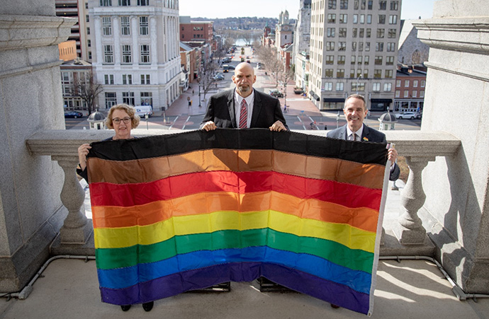 Sen. Santarsiero, with Rep. Wendy Ullman and Lt. Gov. John Fetterman, flying the LGBTQ+ flag on the balcony of the capitol building.